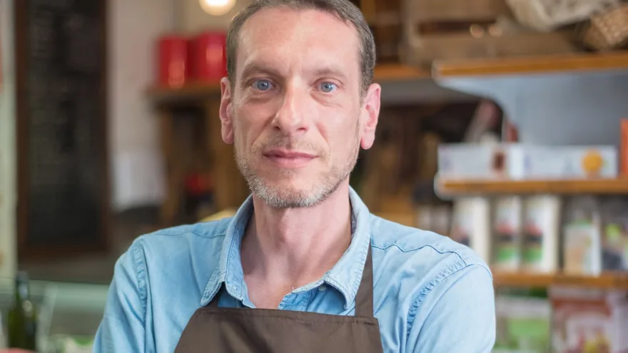 A shopkeeper behind the counter of an independent store